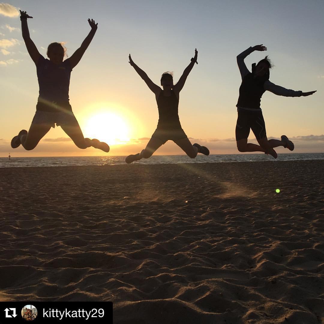 Tri Alliance athletes jumping together on a beach
