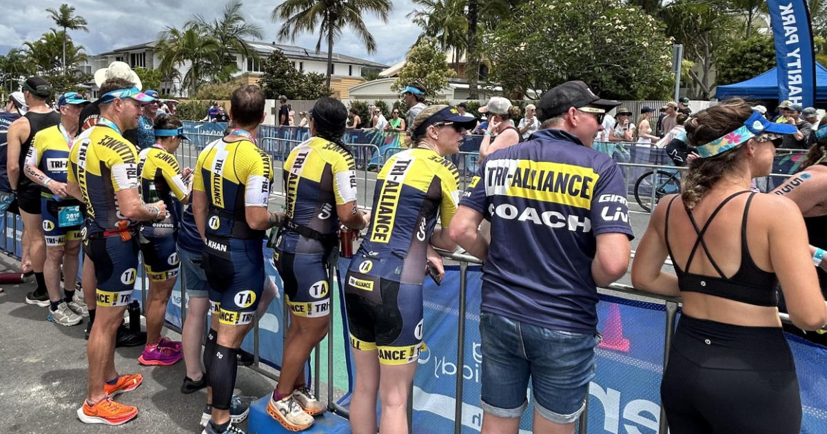 Tri Alliance athletes and coach gathered together beside a race course